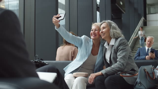Zwei-Freundinnen-mittleren-Alters-machen-Selfie-am-Flughafen