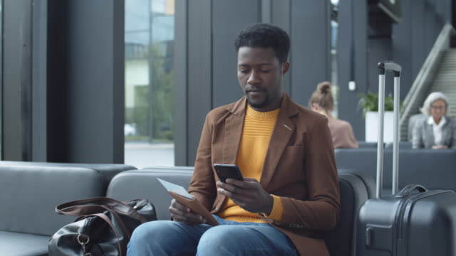 Afrikanischer-Mann-mit-Handy-beim-Warten-am-Flughafen