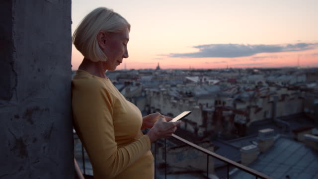 Frau-mittleren-Alters-mit-Smartphone-auf-dem-Dach