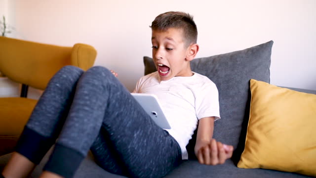 Junge-spielt-Spiele-auf-seinem-Tablet-zu-Hause