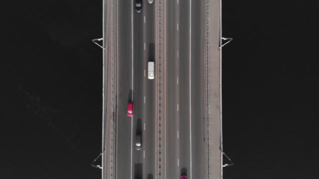 Bridge-highway-dark-water-red-blue-cars-traffic-aerial-top-view