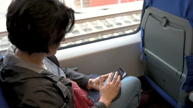 Frau-sitzt-auf-Zug-Halten-Handy-in-ihren-Händen-Klicken-auf-die-hintere-Seite-Ansicht