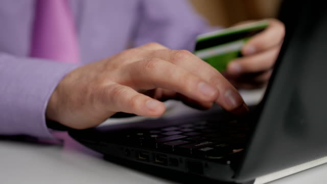 Ein-Geschäftsmann-in-einem-lila-Hemd-und-Krawatte-macht-eine-Zahlung-an-Internet-Banking.-Online-Shopping-mit-Kreditkarte-auf-Laptop.