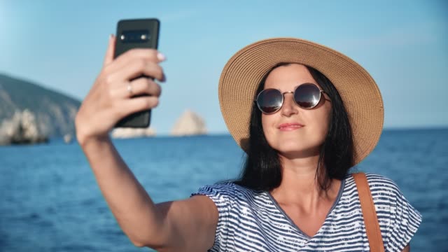 Mujer-joven-alegre-posando-tomando-selfie-utilizar-teléfono-inteligente-en-la-costa.-Toma-de-primer-plano-en-la-cámara-RED-4k