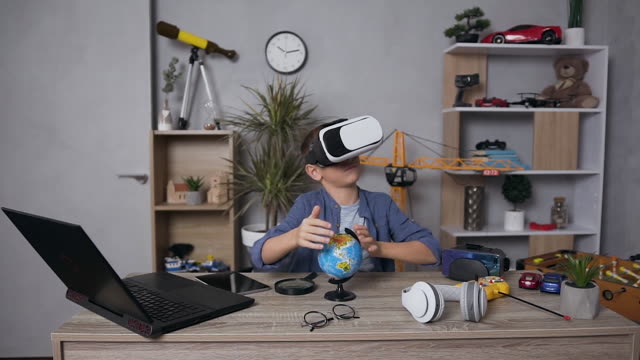 Angenehm-konzentriert-12-alter-interessanter-Junge-arbeiten-mit-kleinen-Globus-mit-speziellen-virtuellen-3D-Brille,-sitzen-in-seinem-Zimmer-am-Tisch