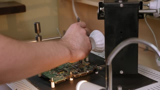 Ein-Reparaturarbeiter,-der-Mikrochips-mit-einem-Föhn-lötet,-während-er-einen-Computer-repariert.