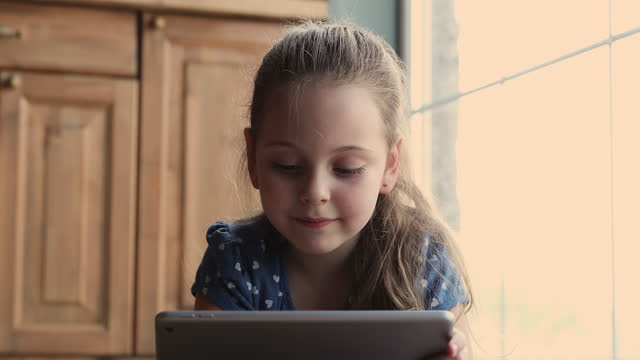 Close-up-view-little-girl-lying-indoor-with-tablet-device