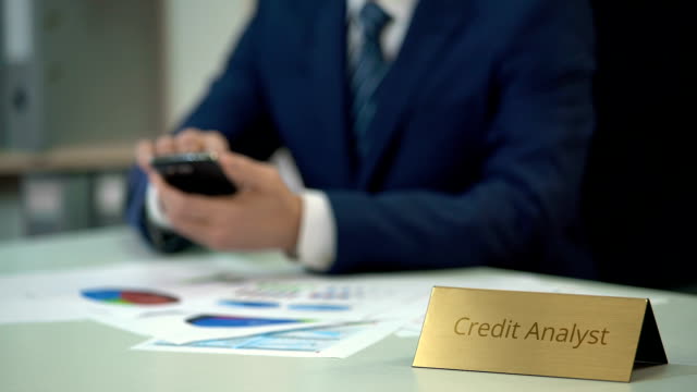 Beschäftigter-Kreditanalyst-mit-Smartphone,-arbeiten-an-der-Finanzgeschichte-des-Unternehmens
