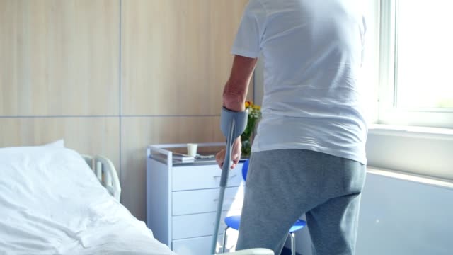 Senior-disabled-man-walking-on-the-crutches-in-the-hospital
