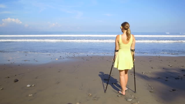 CLOSE-UP:-Strong-independent-woman-with-crutches-on-summer-vacation-at-the-beach