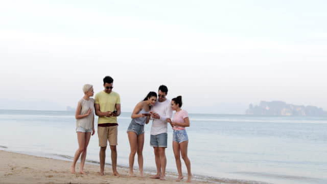 Personas-en-la-playa-usando-redes-celulares-Smart-teléfonos,-grupo-de-turistas-jóvenes-en-línea
