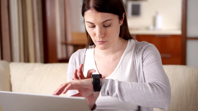 Mujer-en-casa-enviando-el-mensaje-de-audio-mediante-reloj-inteligente.-Joven-mujer-profesional-trabajando-en-smartwatch
