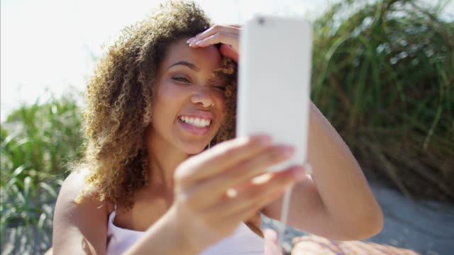 African-American-female-using-smart-phone-on-beach