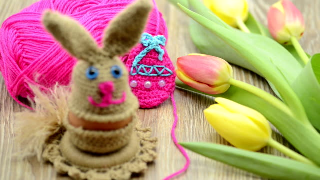 Crochet-Easter-bunny-egg-cup-made-of-wool.-fresh-tulips-and-wool-ball-in-background