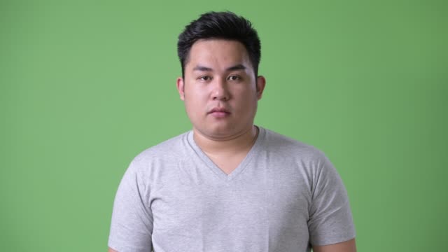 Joven-guapo-sobrepeso-hombre-asiático-sobre-fondo-verde