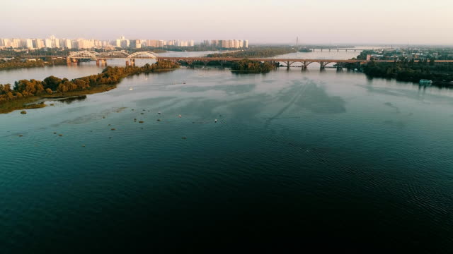 Aerial-view-of-the-Kyiv-city,-Ukraine.-Dnieper-river-with-bridges.-Darnitskiy-bridge.-Poznyaki-district-in-the-background