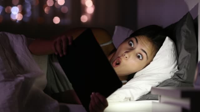 Überrascht-Teen-beobachten-Medien-in-einer-Tablette-in-der-Nacht