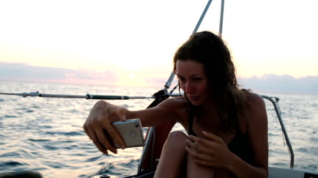 Mujer-joven-navega-el-yate-y-utiliza-un-smartphone---toma-un-selfie