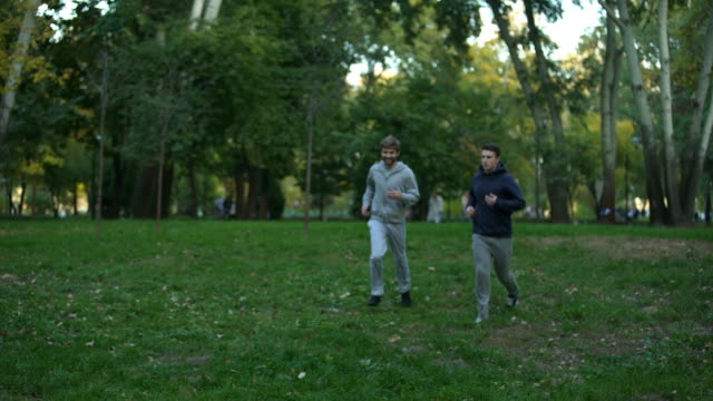 Homosexual-couple-jogging-in-park,-evening-training,-discussing-family-issues