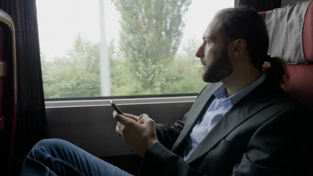Workaholic-business-young-bearded-man-on-train-commuting-to-work-using-smartphone-texting-and-reading-office-emails