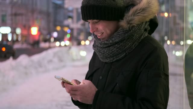 Mann-schreiben-SMS-auf-Handy-im-Schnee-in-der-Nacht