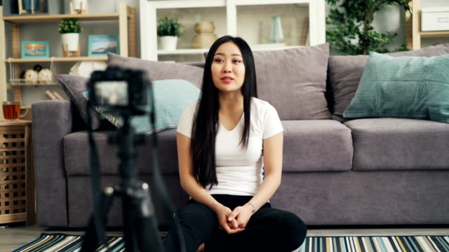 Niedliche-asiatische-Mädchen-Bloggerin-ist-auf-Video-für-ihre-Internet-Vlog-mit-Blick-auf-die-Kamera-und-sprechen-lächelnd-und-lachend.-Blogging-und-Technologie-Konzept.