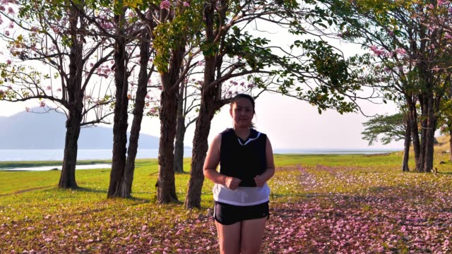 Eine-fette-asiatische-Frau,-die-abends-im-natürlichen-Sonnenlicht-joggt.-Sie-versucht,-mit-Übung-bis-zur-Ermüdung-Gewicht-zu-verlieren.--Konzept-Gesundheit-mit-Bewegung.-Zeitlupe