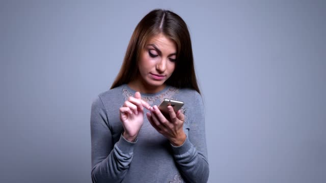 Closeup-portrait-of-modern-young-caucasian-female-using-phone-and-getting-annoyed-while-checking-social-media-posts