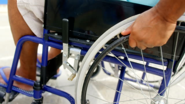 Nahaufnahme-von-behinderten-aktiven,-aktiven,-ranghohen-Afroamerikaner,-der-seinen-Rollstuhl-auf-der-Promenade-4k-bewegt