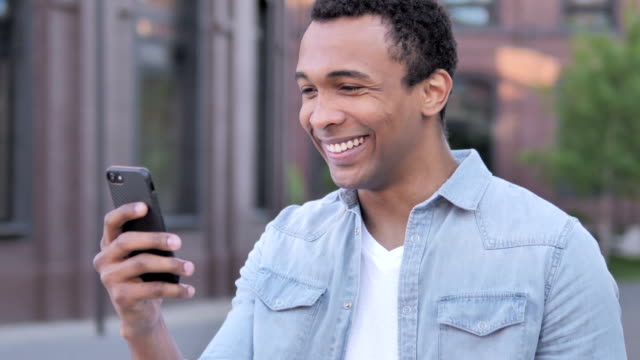 Outdoor-African-Man-Excited-for-Success-on-Phone