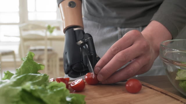 Hombre-discapacitado-con-trianto-biónico-cortando-tomates-cherry