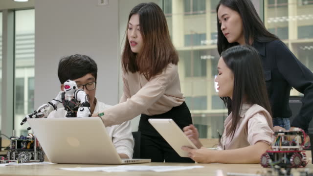 Jóvenes-ingenieros-creativos-asiáticos-reuniéndose,-programación-para-robótica-universal-colaborativa-en-portátil-en-taller.-Personas-con-concepto-de-tecnología-o-innovación.