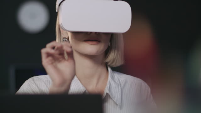 Smiling-woman-testing-computer-program-in-virtual-reality-glasses-in-dark-office.