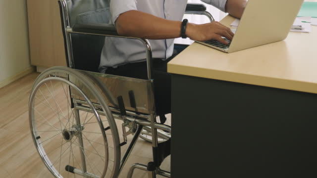 Behinderter-Mann-im-Rollstuhl-arbeitet-im-Büro
