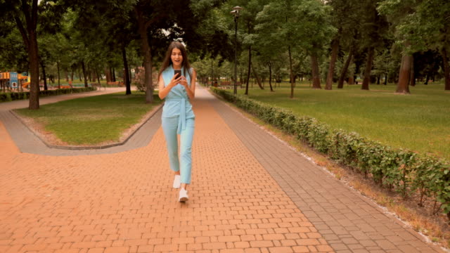 junge-kaukasische-Frau-glücklich-über-gute-Nachrichten-zu-Fuß-auf-der-Straße-im-Stadtpark