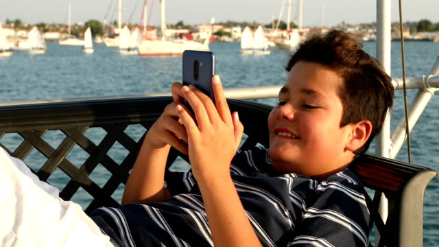 Kind-auf-Yachtdeck-mit-Smartphone