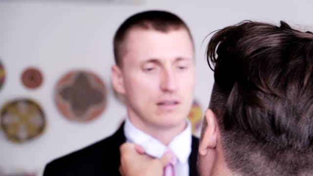 Hombre-gay-ayudar-a-su-pareja-a-poner-corbata-para-la-entrevista-de-trabajo.-Sobre-el-hombro.