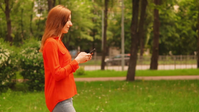 Seitenansicht-Ingwer-Frau-zu-Fuß-auf-der-Straße-halten-Smartphone