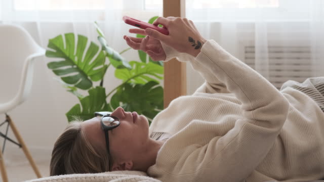 Mujer-relajada-usando-el-teléfono-inteligente-en-la-cama