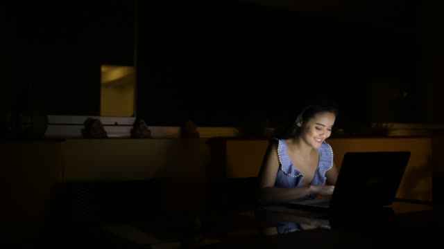 Young-Happy-Asian-Woman-Using-Laptop-In-Dark-Room
