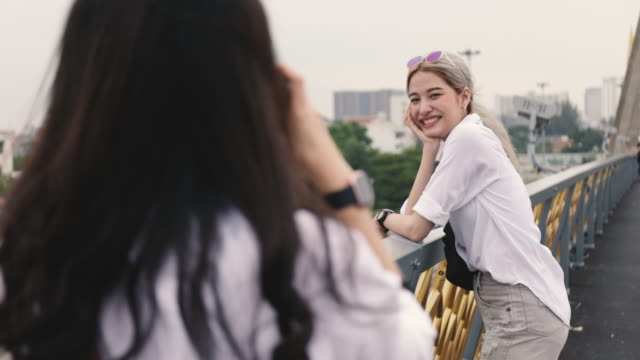 Asian-lesbian-couples-enjoying-traveling-using-film-camera-taking-a-photo.-Two-beautiful-young-women-having-fun-in-vacation-time.-LGBT-concept.