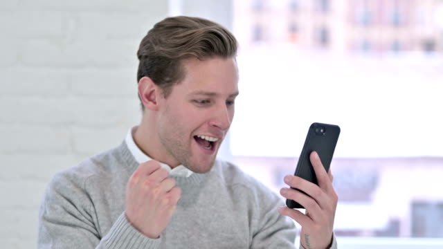 The-Portrait-of-Creative-Young-Man-Celebrating-Success-on-Smartphone