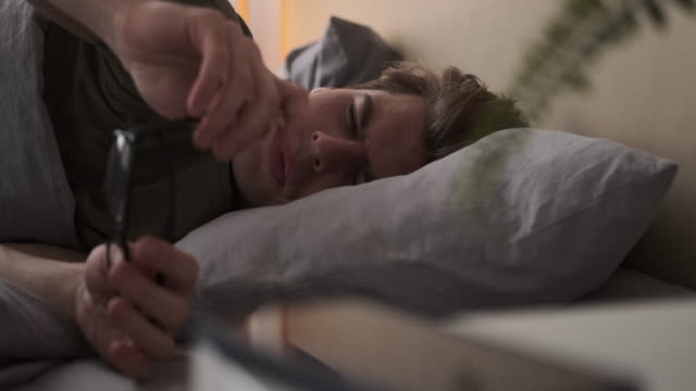 Mann-aufwachen-und-SMS-auf-Handy-im-Bett