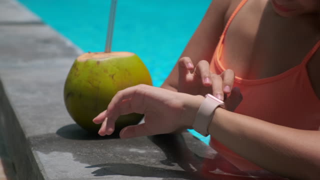 turista-femenina-está-controlando-el-reloj-inteligente-en-la-piscina