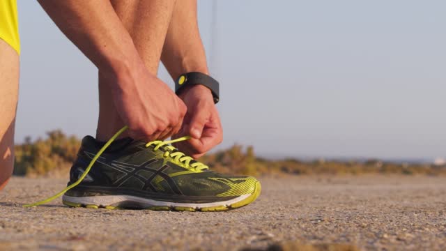 Close-up-of-runner-with-smartwatch-tying-trainers-shoe-laces-outdoors
