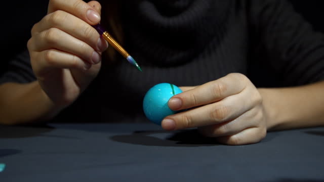 Mujer-manos-de-pintura-de-la-decoración-del-huevo-de-Pascua-sobre-un-fondo-gris.