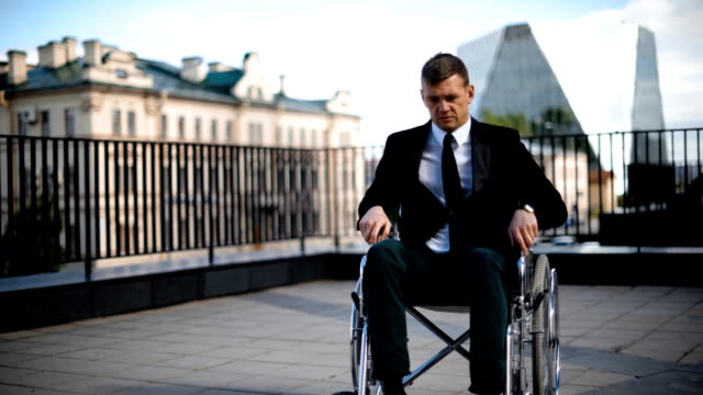 Disabled-businessman-trying-to-get-up-from-wheelchair-outdoor