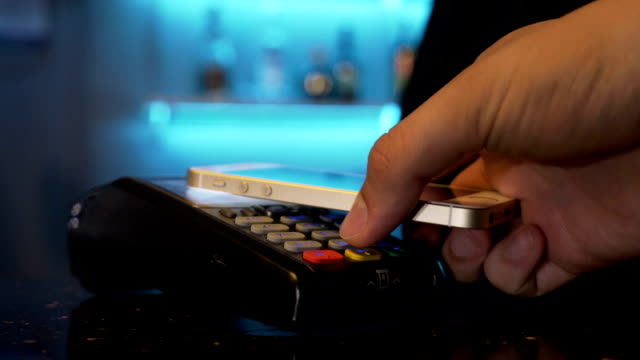 Customer-paying-with-smartphone-at-restaurant-pub-using-pos-and-contactless-wireless-technology