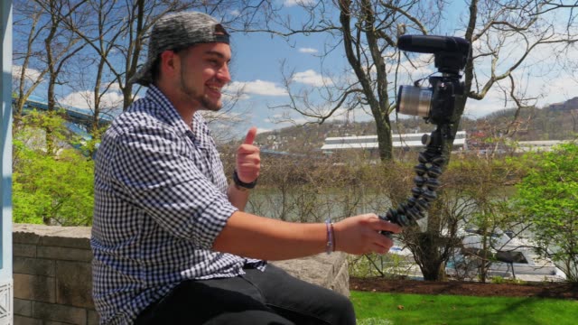Tausendjährige-Vloggerin-sitzt-auf-Wand-und-Aufzeichnungen-Nachricht-vor-der-Kamera