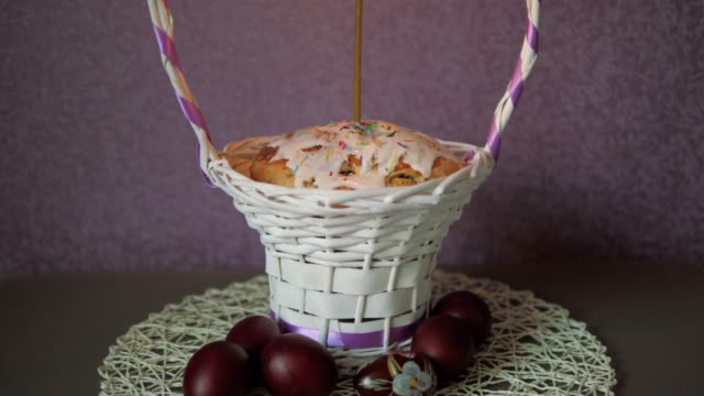 Festliche-Osterkuchen-mit-einer-Kerze-im-Weidenkorb-und-ein-paar-gefärbten-Eiern-unten